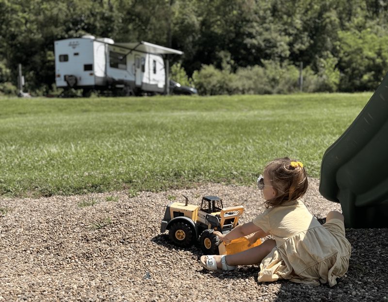 A young child playing with a toy truck beside an RV site at State Line Campground.